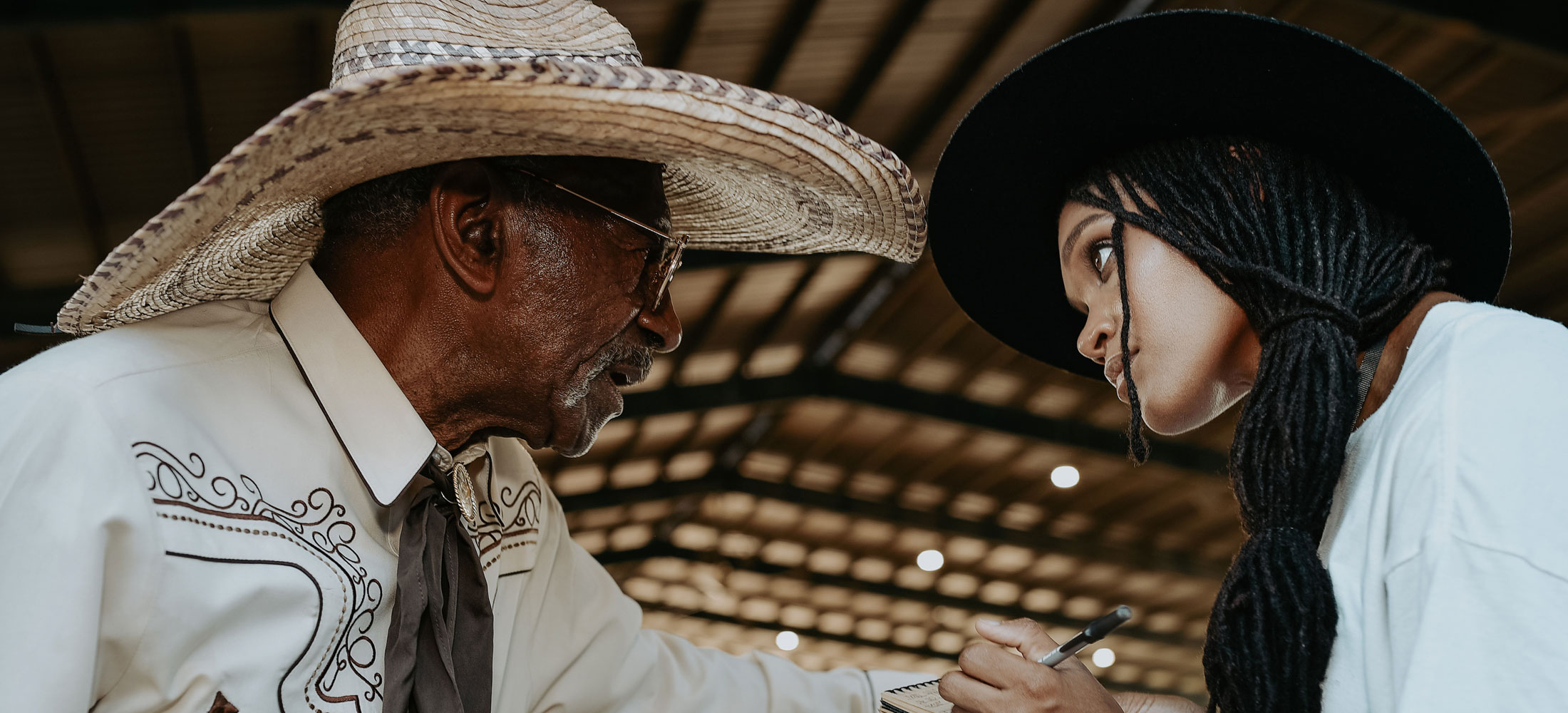 A woman holding a notepad interviewing a cowboy, BPIR contestant Adam Ezell Jr.